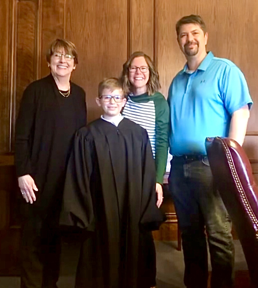 10-year-old boy tries on Supreme Court of Missouri Judge Patricia Breckenridge's judicial robe during his family's tour of the Court building March 1, 2022